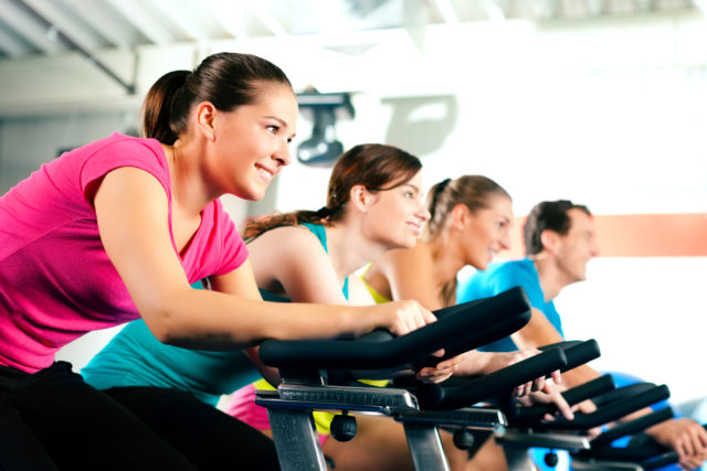 Group Of Four People In The Gym, Exercising Their Legs Doing Cardio Training