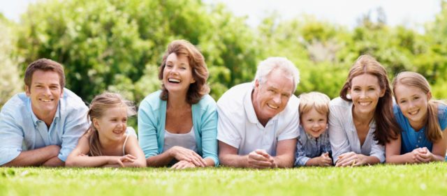 Smiling and happy family lying together on the grass outdoors