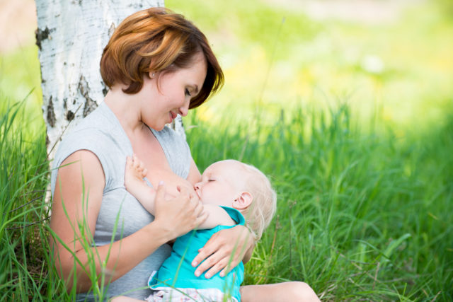 Young mother breastfeeding a baby in nature