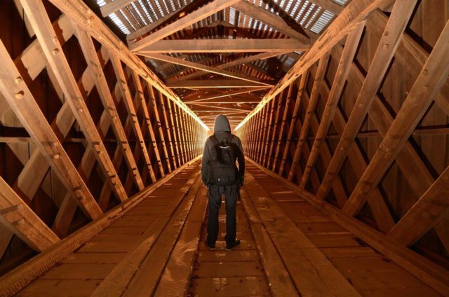 person-standing-in-wooden-tunnel-example-of-converging-leading-lines-in-photography